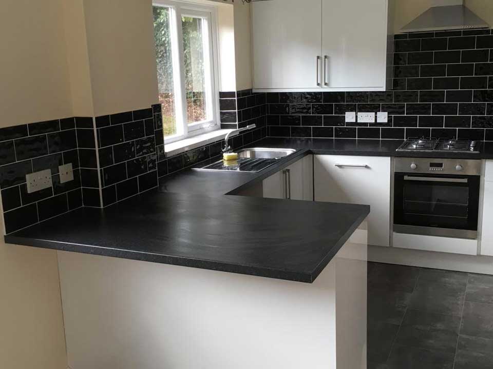 Completed kitchen renovation with flooring and dark tiles.
